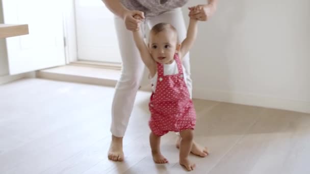 Emocionada niña dando sus primeros pasos con la ayuda de la madre. — Vídeo de stock