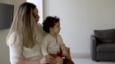 Mutlu kıvırcık saçlı çocuk, dizlerinin üstüne çöküp eğleniyor..