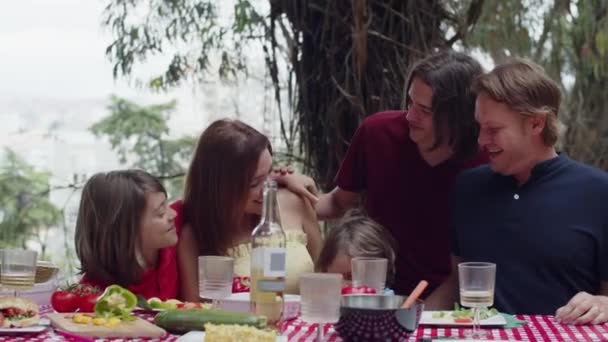 Família sentada junto à mesa, abraçando, sorrindo e conversando — Vídeo de Stock