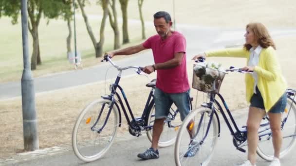 Szczęśliwa para seniorów spacerująca rowerami po ścieżce w parku — Wideo stockowe