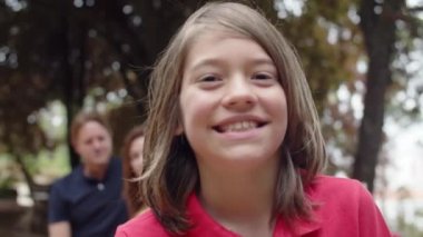 Genç bir çocuğun kameraya bakıp gülümsediği yakın çekim.