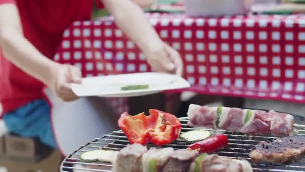 Közelkép egy felismerhetetlen férfiról, aki grillezett húst tesz tányérra. — Stock videók