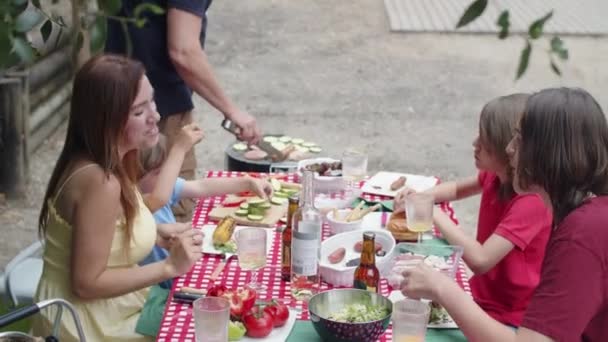 自然の中で夕食のための幸せな家族の集まりの垂直運動 — ストック動画