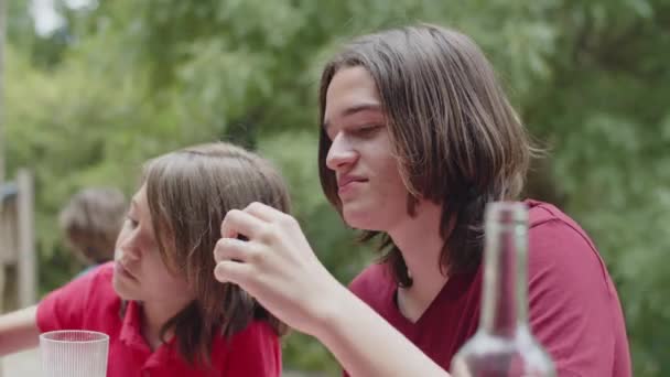 Irmãos felizes sentados à mesa e comendo churrasco no piquenique — Vídeo de Stock