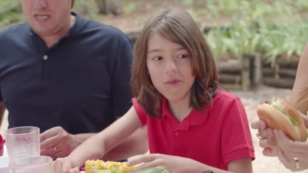 Κοντινό πλάνο του χαρούμενου αγοριού που τρώει μπέργκερ στο πικνίκ — Αρχείο Βίντεο