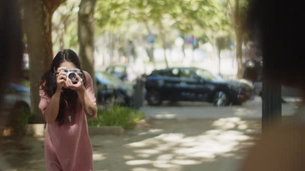 年轻的女摄影师为公园里的人拍照 — 图库视频影像