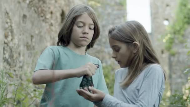 Schwerer blonder Junge schenkt Mädchen magische Steine — Stockvideo