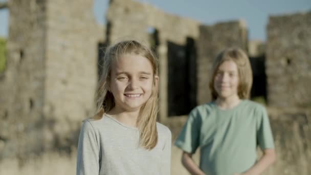 ภาพกลางของเด็กผู้หญิงและเด็กชายที่มีความสุข มองไปที่กล้องในวันที่แดด — วีดีโอสต็อก
