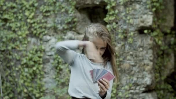 Funny girl standing among walls of old castle and reading cards — Stock Video