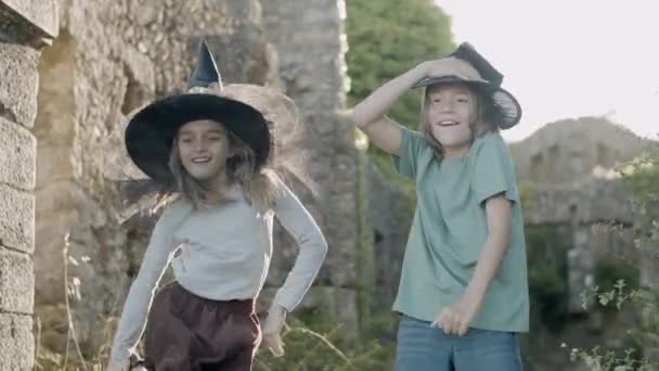 Niños felices de pie entre las paredes de piedra del castillo y el baile — Vídeo de stock