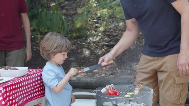 Заботливый отец дал своему сыну попробовать барбекю. — стоковое видео