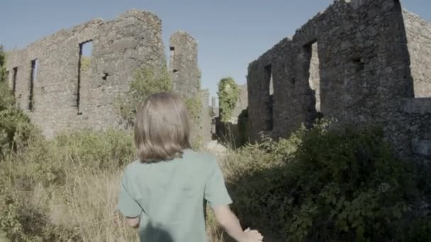 Indietro vista bambini a piedi tra le mura di pietra di antico castello — Video Stock