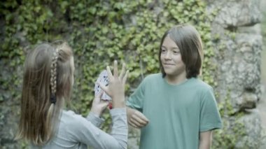 Neşeli beyaz çocuk, kızların elinden kart çekiyor.