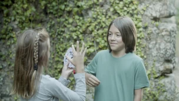 Wesoły biały chłopiec wyciąga kartę z rąk dziewcząt — Wideo stockowe