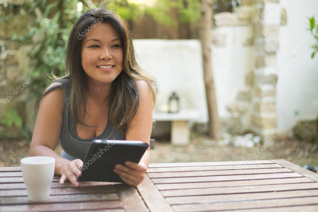Attractive Japanese young woman using tablet in outdoor cafe