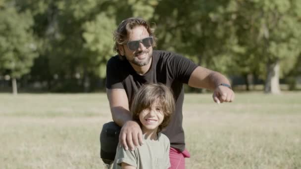 Отец-инвалид сидит с сыном на газоне в парке — стоковое видео