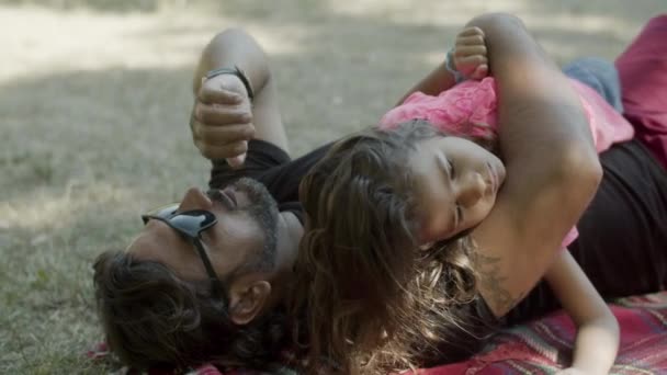 Tired daughter lying with dad on blanket during picnic — Stock Video