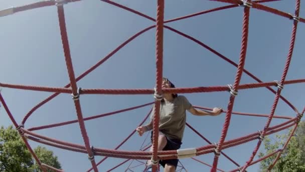 Zaměřený chlapec cvičení na lano atrakce v letním parku — Stock video