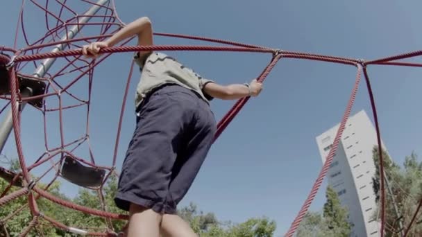 集中精神的男孩在操场上攀爬绳索的背景图 — 图库视频影像