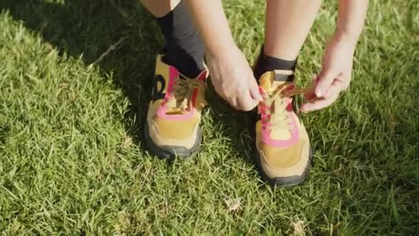 Mediana toma de mujer atando zapatillas en el parque de verano — Vídeos de Stock