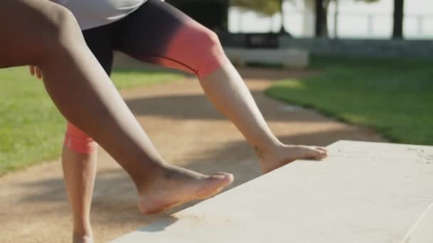 Medelhög bild av barfota vänner stretching ben i offentlig park — Stockvideo