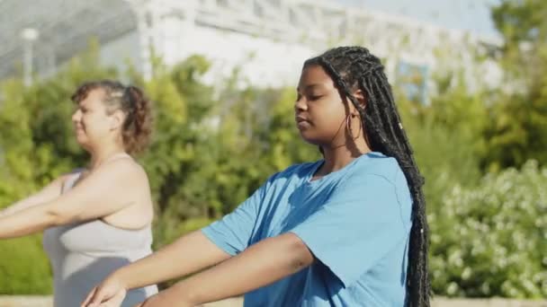 Movimento lento de meninas gordas aquecendo antes do treino ao ar livre — Vídeo de Stock