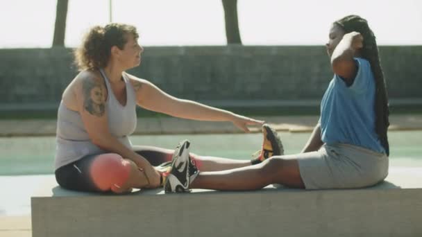 Largo tiro de amigos felices estirando las piernas en el campo de deportes — Vídeos de Stock