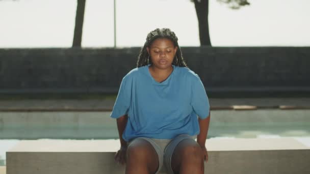 Вид спереду зосереджена товста жінка робить присідання вправи в парку — стокове відео
