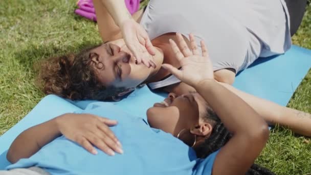 Handheld schot van uitgeputte vrouwen liggend op mat na training — Stockvideo
