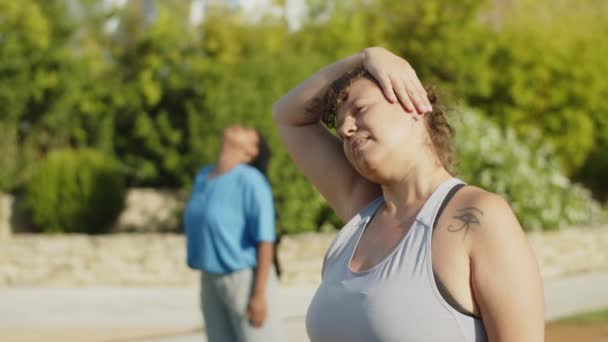 Foto media de mujer alegre estirando los músculos del cuello en el parque — Vídeos de Stock