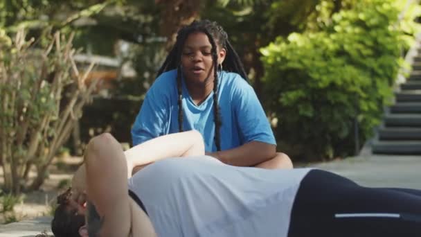 Afroamerikanerin feuert ihren Freund an, der Bauchmuskeln trainiert — Stockvideo
