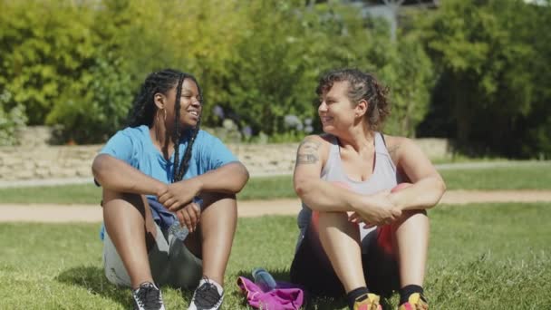 Long shot de femmes grasses heureux assis sur la pelouse après l'entraînement — Video