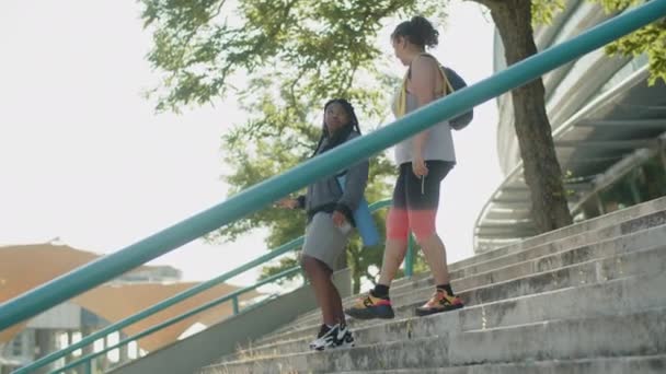 Largo tiro de mujeres gordas bajando escaleras de complejo deportivo — Vídeo de stock