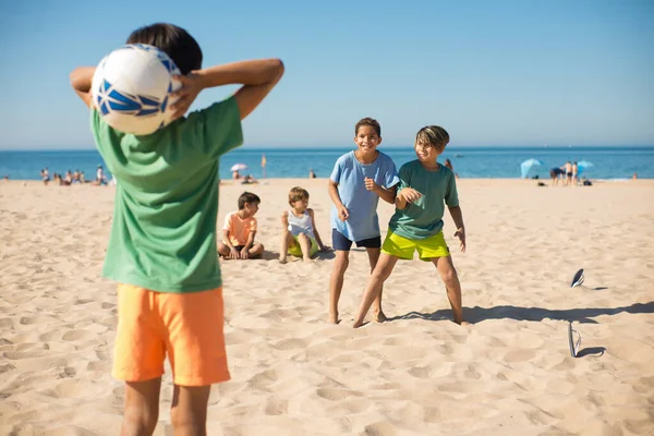 Neşeli erkek arkadaşlar sahilde futbol oynuyorlar. — Stok fotoğraf