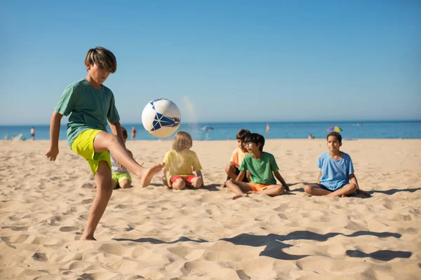 Ragazzo concentrato che gioca con la palla sulla spiaggia — Foto Stock