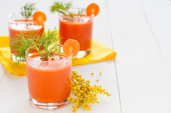 Морковный сок в стаканах и ветке мимозы — стоковое фото