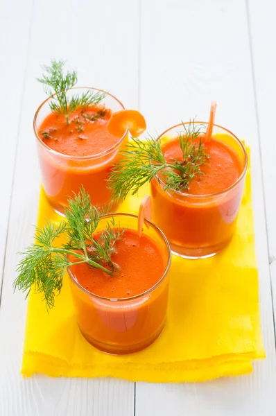 Три стакана морковного сока на желтой салфетке — стоковое фото