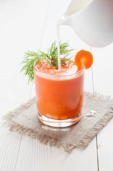 Морковный сок в стакане, и наливать молоко — стоковое фото
