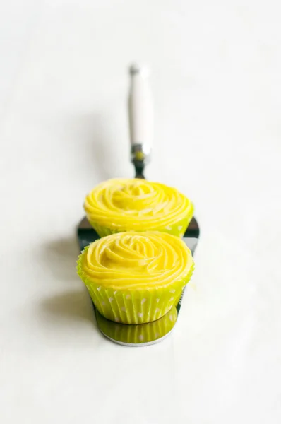 Gelbe Cupcakes auf Kuchenschaufel, weißer Hintergrund. — Stockfoto