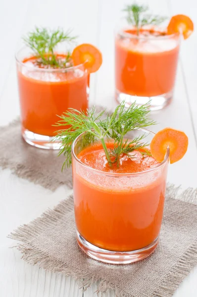 Три стакана морковного сока на льняной салфетке — стоковое фото
