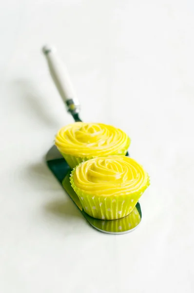 Жовті кекси на лопаті для торта, білий фон . — стокове фото