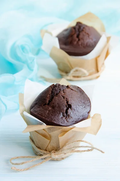 Muffins de chocolate em embrulho em mesa de madeira — Fotografia de Stock
