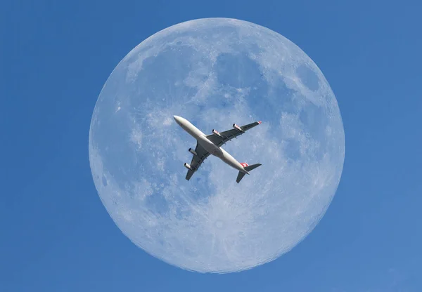 在蓝天中央的月亮前的一架飞机 — 图库照片