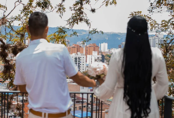 newly married couple with their backs turned against the background of a city