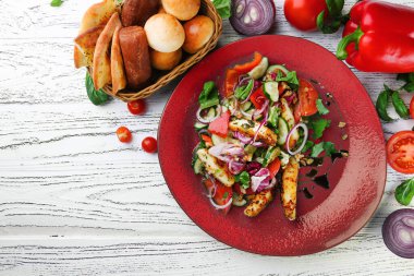 Tavuklu salata ve ahşap masa manzaralı sebzeler.