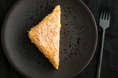 Tabakta Napolyon keki ve arka planda koyu renk üst görünüm.