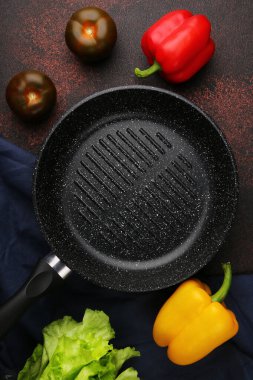 Taze sebzeli boş ızgara tavası ve metal mutfak tezgahında baharatlar.