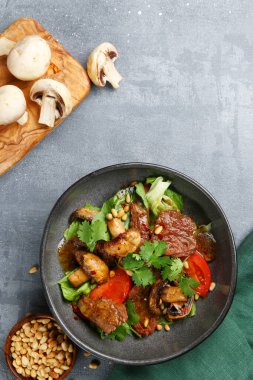 Çam fıstığı manzaralı sığır ve şampiyonlar. Beton masada sığır eti ve mantar salatası.
