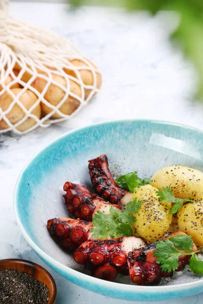Izgara ahtapot ve patates. Ahtapot salatası ve malzemeler masanın üstünde..