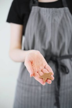 Noel zencefilli kurabiyeleri yakın plan tatlı. Önlüklü kadın elinde çiğ zencefilli kurabiye.